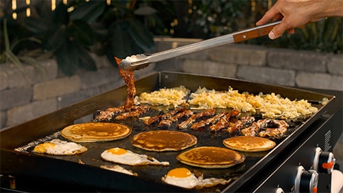 hashbrowns, bacon, pancakes and eggs on a gas griddle