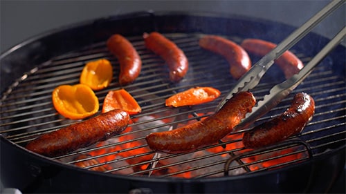 sausages and peppers on a charcoal grill