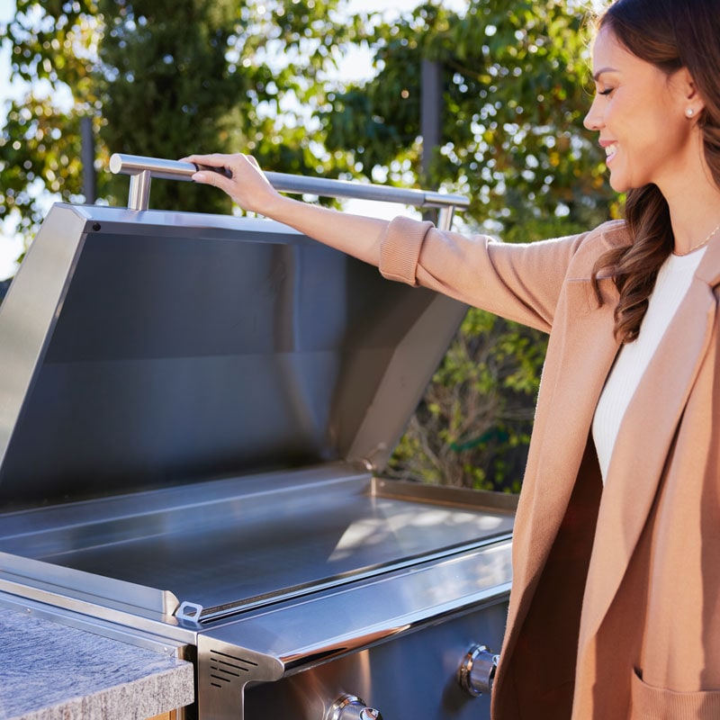 Woman lifting lid of Blaze Gas Griddle