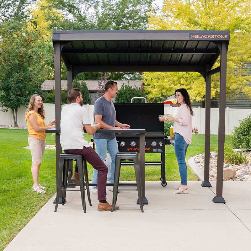 people grilling on a gas griddle under a patio pergola