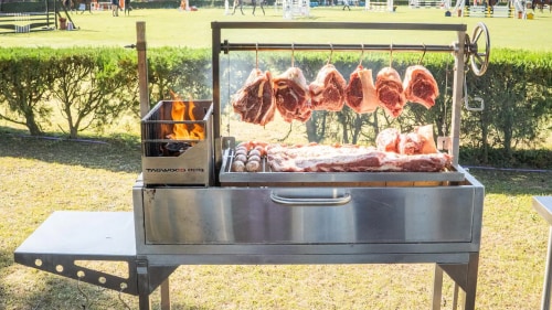 santa maria grill with hunks of meat hanging over the fire