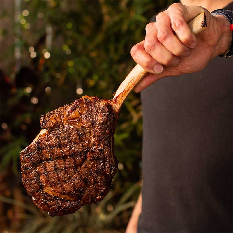 Chef Tony holding up a reverse seared tomahawk steak