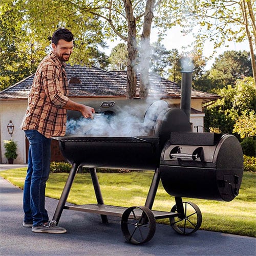 man opens oklahoma joe's offset smoker revealing smoke and food