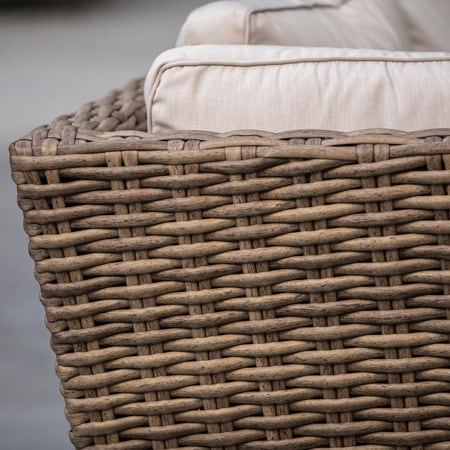 Close-up of a woven resin wicker chair arm with a cream cushion