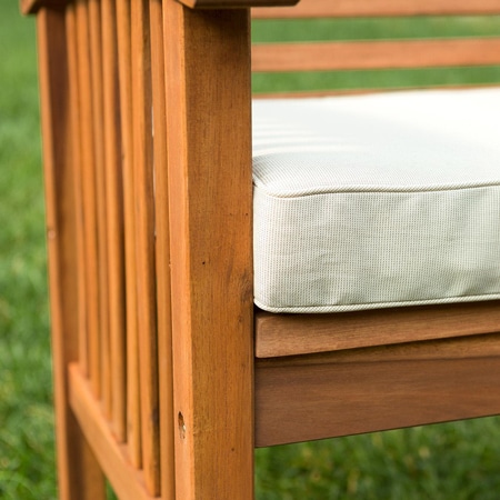 Close-up of a wood chair armrest and cream cushion outdoors on grass