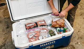 An ice chest, packed with ice, cooling proteins prior to grilling