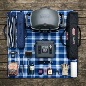 Essential supplies for a successful tailgate, arranged on a tablecloth