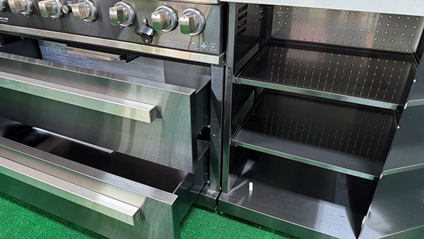 Storage cabinets and drawers open on the Mont Alpi Black Series outdoor kitchen island
