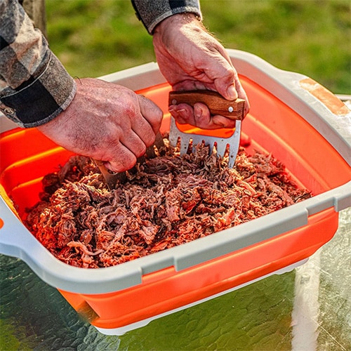 Man shredding pulled pork in the Drip EZ BBQ Prep Tub