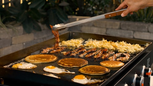 Griddle breakfast spread with eggs, bacon, pancakes, and hash browns