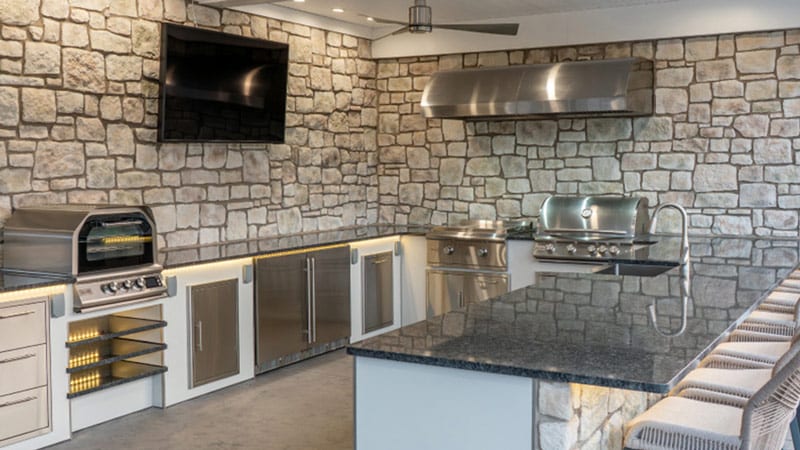 U-shaped outdoor kitchen featuring Blaze gas grill, griddle, and pizza oven